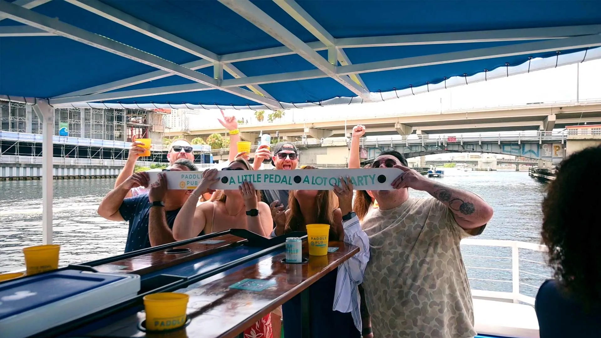 A Paddle Pub Tampa crew raising a toast aboard the pedal boat on the Riverwalk